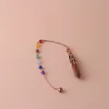Dettaglio di pendolo esagonale in pietra dorata con sette perle chakra e catena oro rosa. - Pietra Arenaria Dorata