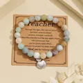 Detailed view of natural stone beads and silver apple charm on a kraft gift card - Amazonite