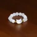 Detailed macro view of a beaded ring with white shell pearls and a cat head charm - Cat / Silver White