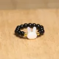 Detailed view of handmade elastic ring with black beads and white shell rabbit - Rabbit / Black and White