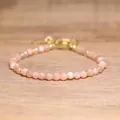 Detailed view of faceted natural peach stone beads on a gold adjustable bracelet. - Sunstone