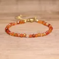 Close-up of faceted natural orange stone beads on an adjustable gold bracelet - Red Agate
