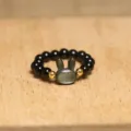 Macro detail of a cute grey shell rabbit beaded elastic ring on a wooden surface - Rabbit / All Black
