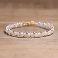 Handmade white Tila bead and gold accent woven bracelet displayed on a natural wood surface - White Moonstone