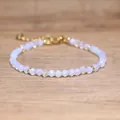 Close-up view of faceted opal-like beaded bracelet with adjustable gold chain on wood. - Opal
