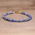 Close-up detail of blue faceted natural stone beaded bracelet with gold-tone accents - Sodalite