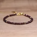 Detailed macro view of faceted burgundy stone beads with elegant gold spacer beads - Garnet