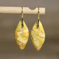 Detail van elegante druppeloorbellen van gele keizerlijke steen op houten display - Natuurlijke Vorm 3