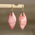 Detailaufnahme von rosa marmorierten Jaspis-Ohrhängern an einem natürlichen Holzstab - Natürliche Form 8