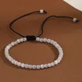 Detailed view of 4mm natural white stone beads on an adjustable black woven bracelet. - White Cat's Eye
