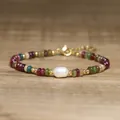 Handmade tourmaline beaded bracelet with a baroque pearl on a wood surface - Rainbow