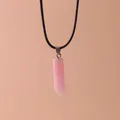 Close-up of a pink hexagonal crystal quartz column pendant necklace on a black cord - Cherry Jasper
