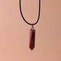 Close-up detail of a hexagonal red jasper stone pillar pendant on a black cord necklace - Red Sandstone