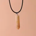 Close-up of hexagonal pillar quartz crystal pendant on a black cord necklace - Topaz