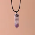 Close-up of a hexagonal purple crystal pillar pendant hanging on a simple black cord - Amethyst