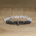 Detailed view of a gothic skull charm bracelet featuring hematite beads on wood - Crystal White