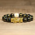 Vue détaillée d'un charme Pixiu doré sur un bracelet de richesse en perles noires. - Perles Mantra Noires (1)