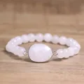 Gedetailleerde close-up van een witte natuurstenen kralenarmband met ovale hanger. - Bergkristal