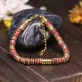 Dettaglio di perle in pietra rossa e distanziatori dorati in acciaio su bracciale regolabile - Rosso Sesamo