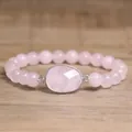 Gros plan d'un bracelet en quartz rose naturel avec un grand pendentif en pierre facettée. - Quartz rose