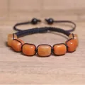 Primo piano dettagliato di perle in pietra naturale arancione su un braccialetto yoga chakra - Avventurina Gialla / Giallo