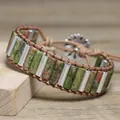 Macro detail of a handmade woven bracelet featuring green natural stones and silver tubes - Unakite