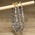 Detailed view of grey marbled stone bead necklaces hanging on a wooden stick display - Gray and White