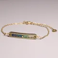 Detailweergave van een goudkleurige schakelarmband met een bar-hanger met gekleurde kralen - Blauwe en Witte Verloop Natuursteen