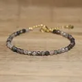 Detailed view of faceted natural stone beads and gold-tone adjustable clasp on a bracelet - Black and White