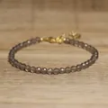 Detail view of a faceted smoky natural stone beaded bracelet with gold clasp. - Light Gray