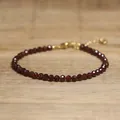 Detailed view of faceted dark red gemstone beads on an adjustable gold chain bracelet. - Dark Red