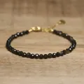 Close-up of faceted dark natural stone beads on a delicate adjustable gold bracelet - Black & Gold