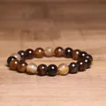 Macro shot of 8mm natural Indian agate beaded bracelet on a warm wooden background. - Coffee Striped Agate