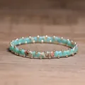 Handmade turquoise and gold beaded elastic bracelet for men and women on wood surface - Green Shoushan Stone