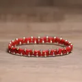 Handmade red stone and gold bead stretch bracelet presented on a wooden surface. - Red Howlite with Black Veins
