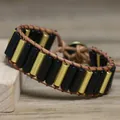 Macro detail of hand-woven bracelet with black and gold cylindrical beads on leather - Black Agate