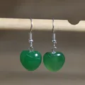 Detail showing green heart-shaped natural stone dangle earrings on wooden hanger - Heart Shape 5 (Green Aventurine)