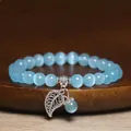 Close-up of blue cat's eye stone bead bracelet with detailed silver leaf charm - Lake Blue