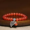 Macro detail of orange cat's eye bead bracelet with silver-tone leaf charm - Dark Red