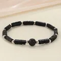 Detail view of a handcrafted black lava stone bracelet featuring decorative silver beads - Volcano