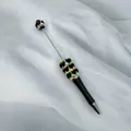 Handmade black beadable pen featuring colorful heart candy beads on white textured fabric - Black