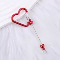 Red electroplated heart-shaped carabiner keychain with beaded detail on white fur background - Red
