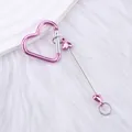 Pink heart-shaped carabiner keychain with heart beads and metal rod on white fur - Pink