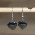 Detail shot of heart-shaped natural stone earrings hanging on a light wooden bar. - Heart Style 8 (Dark Gray Stone)