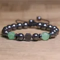 Gedetailleerd overzicht van gefacetteerde hematiet en groene stenen armband met Om-bedel - Groene Aventurijn