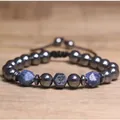 Detailopname van hematiet kralenarmband met blauwe lapis lazuli en Om-symbool bedel. - Sodaliet