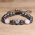 Gedetailleerd macro-overzicht van hematiet kralen en rozenkwarts met Om-symbool op armband - Rozenkwarts