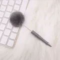 Elegant grey pom-pom ballpoint pen on a white faux fur background with a keyboard - Gray