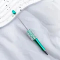 Turquoise beadable ballpoint pen with elegant pearl and rhinestone accents on white fabric - 1.0mm Bullet Tip / UV Green