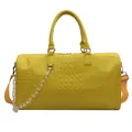 Detailed view of a stylish large yellow crocodile-pattern travel duffel bag with chain - Yellow